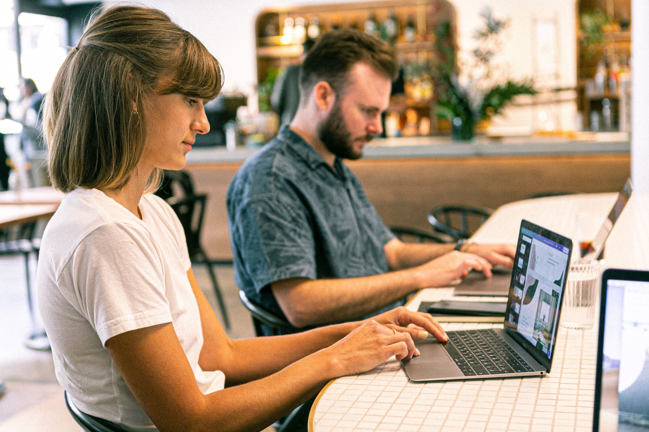 man and woman at work desk with laptops